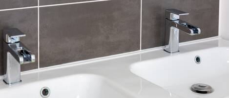 A bathroom with two sinks and chrome faucets.