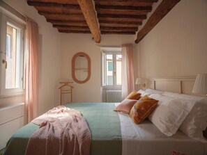 A bedroom with a bed, a mirror, a window, and a radiator. - One Bedroom Apartment (Lucca)