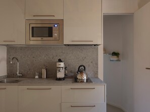 A modern kitchen with a built-in microwave, a coffee machine, and a kettle. - One Bedroom Apartment (Lucca)