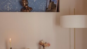 A wooden desk with a book, a candle, and a vase with dried flowers.