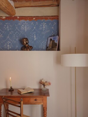 A wooden desk with a book, a candle, and a vase with dried flowers. - One Bedroom Apartment (Lucca)
