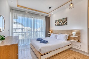 A modern hotel room with a large bed, a wooden desk, a bedside table, a wall-mounted lamp, and a view of the sea. - Luxury duplex apartment, sun terrace, jacuzzi SDIN1-1 (Swieqi)