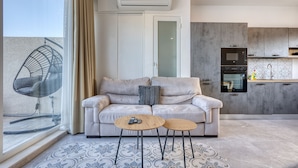 A modern living room with a sofa, two side tables, a chair, and a large window. - Luxury duplex apartment, sun terrace, jacuzzi SDIN1-1 (Swieqi)