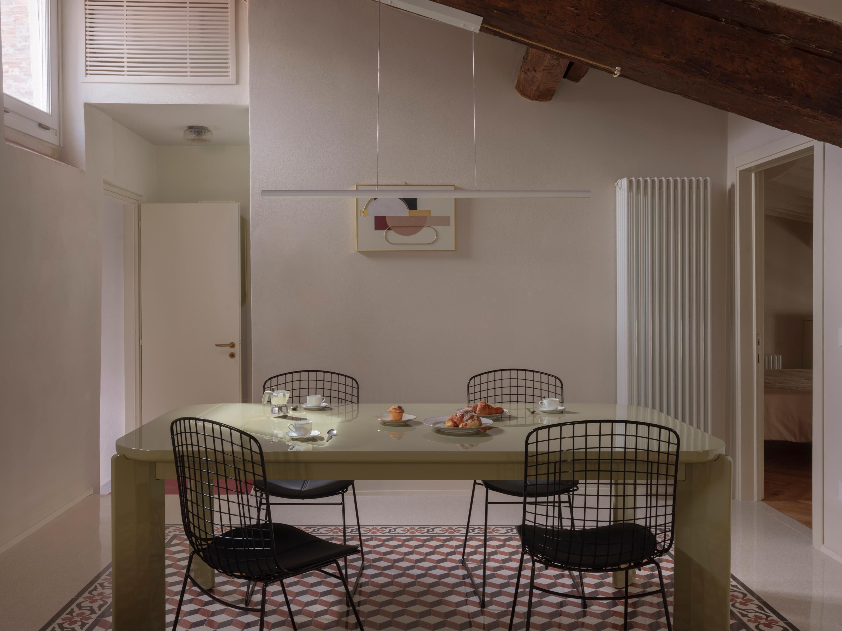 A dining area with a table set for two, featuring black wire chairs and a patterned floor.