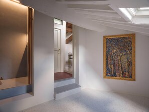 A hallway with a door, a staircase, and a framed artwork on the wall. - One Bedroom Apartment (Lucca)