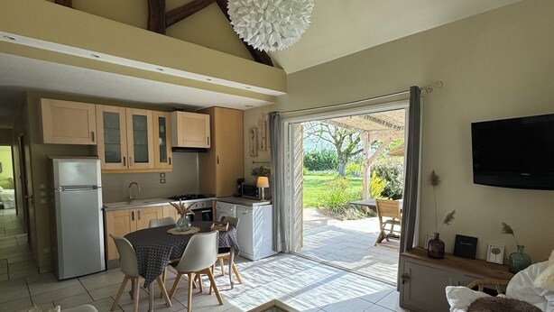 A spacious living area with a dining table, sofa, and a kitchen in the background. - Charming gîte near the Côte Viticole (Chevigny-en-Valière)