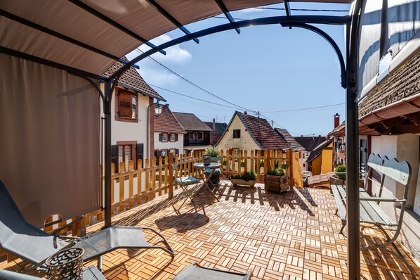 A courtyard with a wooden fence, outdoor seating, and a view of surrounding buildings.