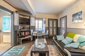A compact living space with a sofa, a dining table, a kitchen area, and a bookshelf.