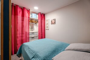 A bedroom with a bed, a wardrobe, and a shelf with items.