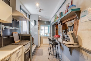 A modern kitchen with a built-in oven, a coffee machine, and a bar area with stools.