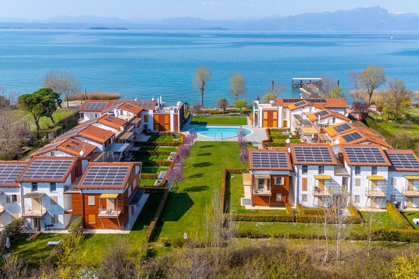 A modern residence on Lake Garda featuring apartments, a central pool, and spacious green areas. The property is located right on the lake, offering a peaceful and scenic setting that’s ideal for relaxing vacations surrounded by nature and comfort.