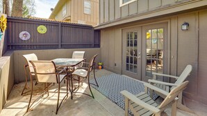 Eine Terrasse mit Tisch und Stühlen, ein Holzzaun und ein Gebäude mit Fenster und Tür.