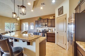 A kitchen with a granite island, stainless steel appliances, and pendant lighting. - Hike, Golf & Try Your Luck! Mtn-view Mesquite Home (Mesquite)