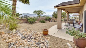 A patio area with a cactus plant, a palm tree, and a covered seating area with outdoor furniture. - Hike, Golf & Try Your Luck! Mtn-view Mesquite Home (Mesquite)