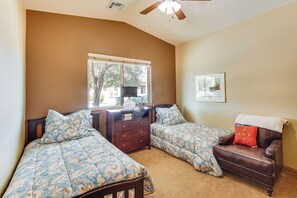 A bedroom with two beds, a dresser, a chair, a ceiling fan, and a window.
