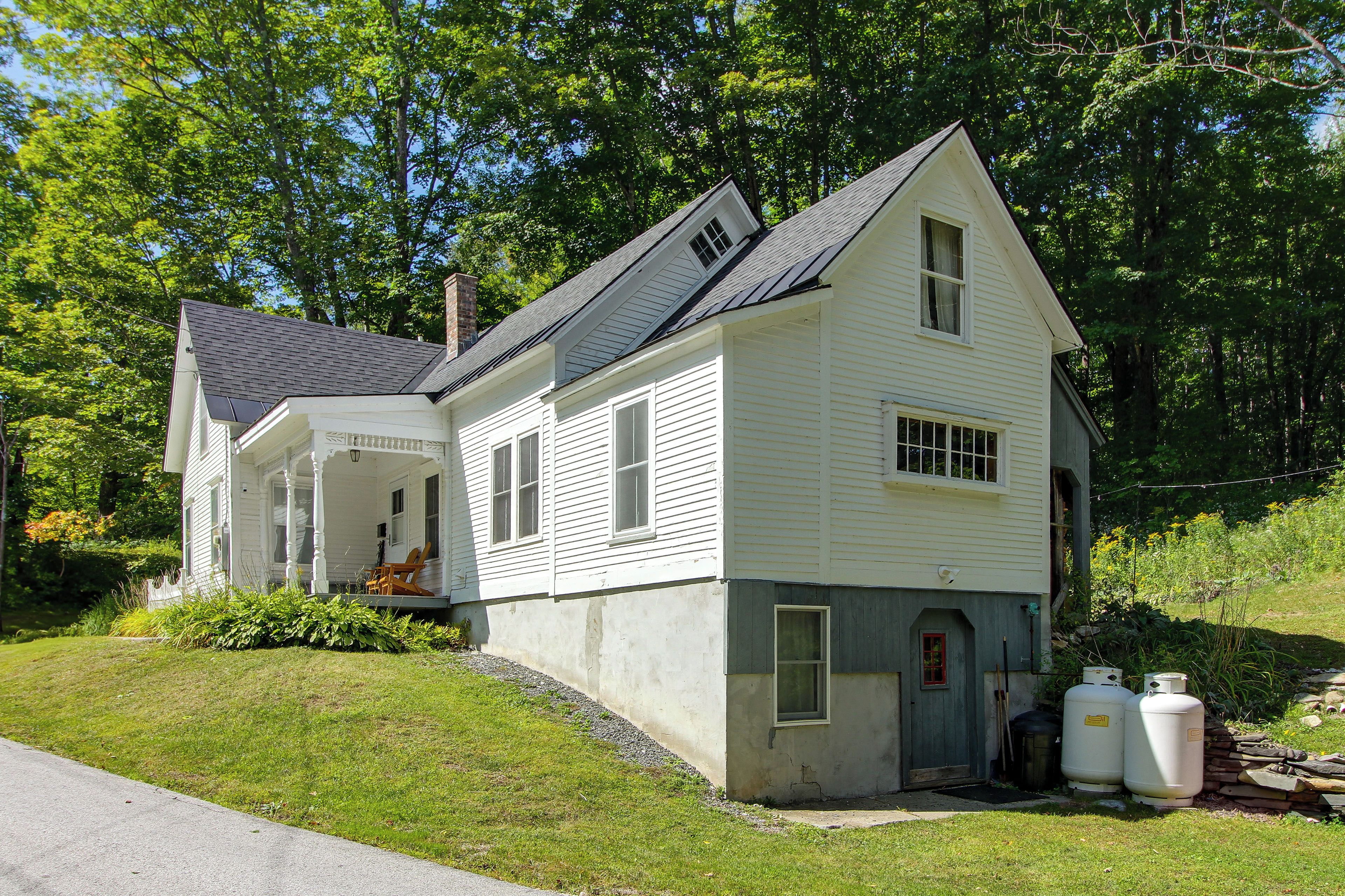 A two-story white house with a porch and a small attached garage.