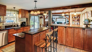 Una cocina amplia con armarios de madera, una isla central con taburetes de bar e iluminación colgante.