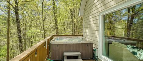 A hot tub on a wooden deck with a view of a forest.