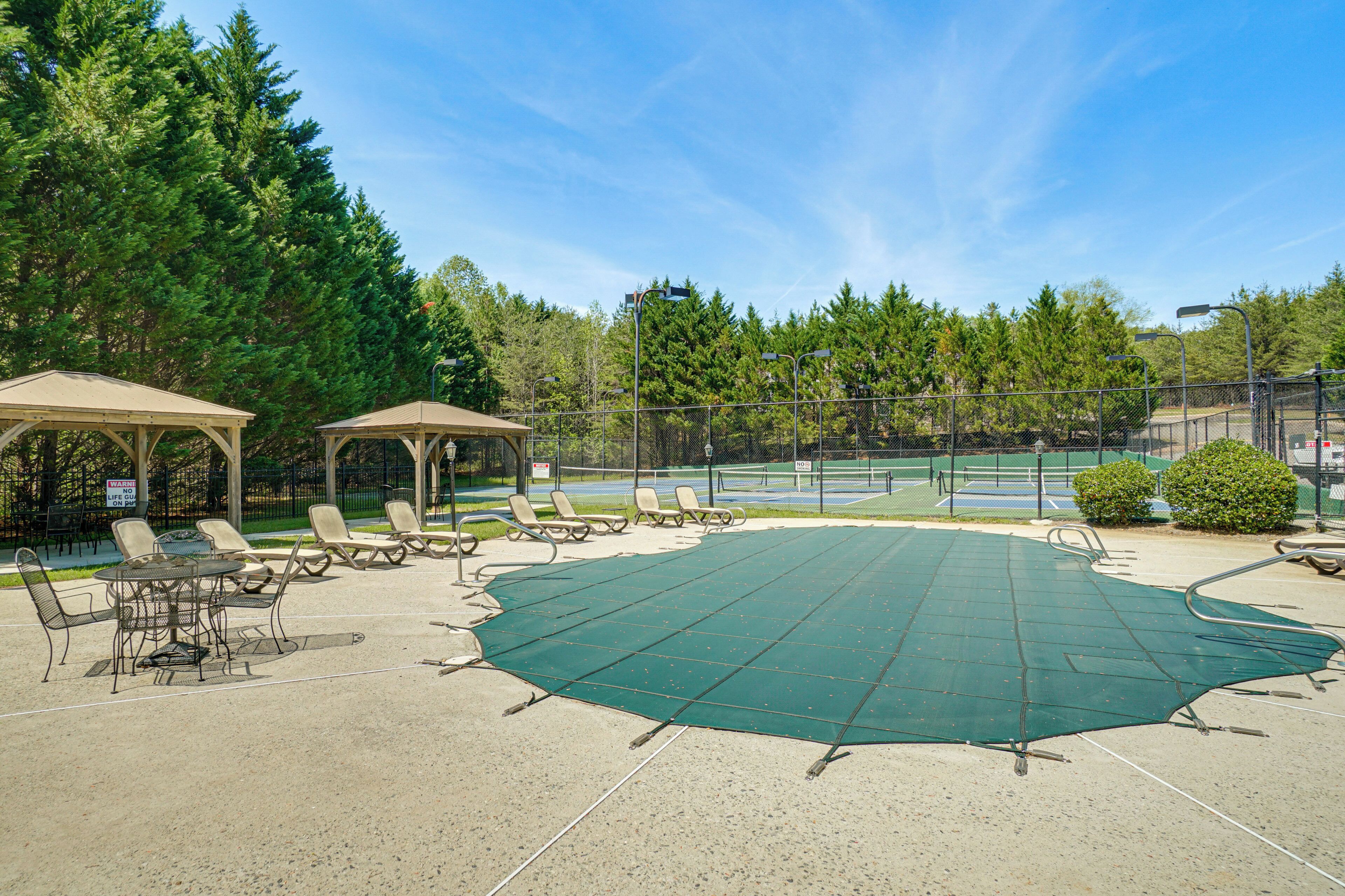 An outdoor patio area with a tennis court, lounge chairs, and a gazebo.