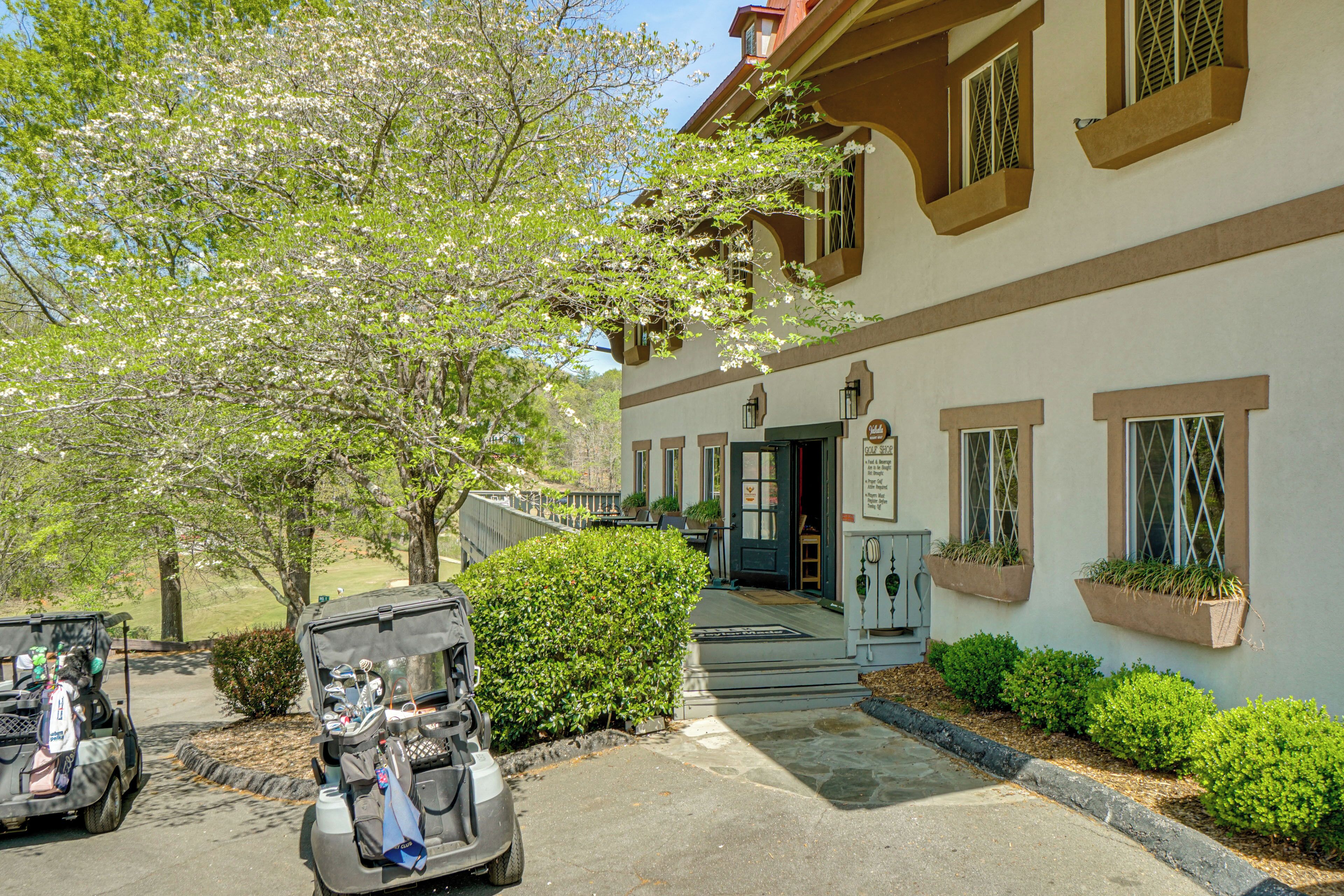 A building with a porch, a golf cart, and a tree with white blossoms.