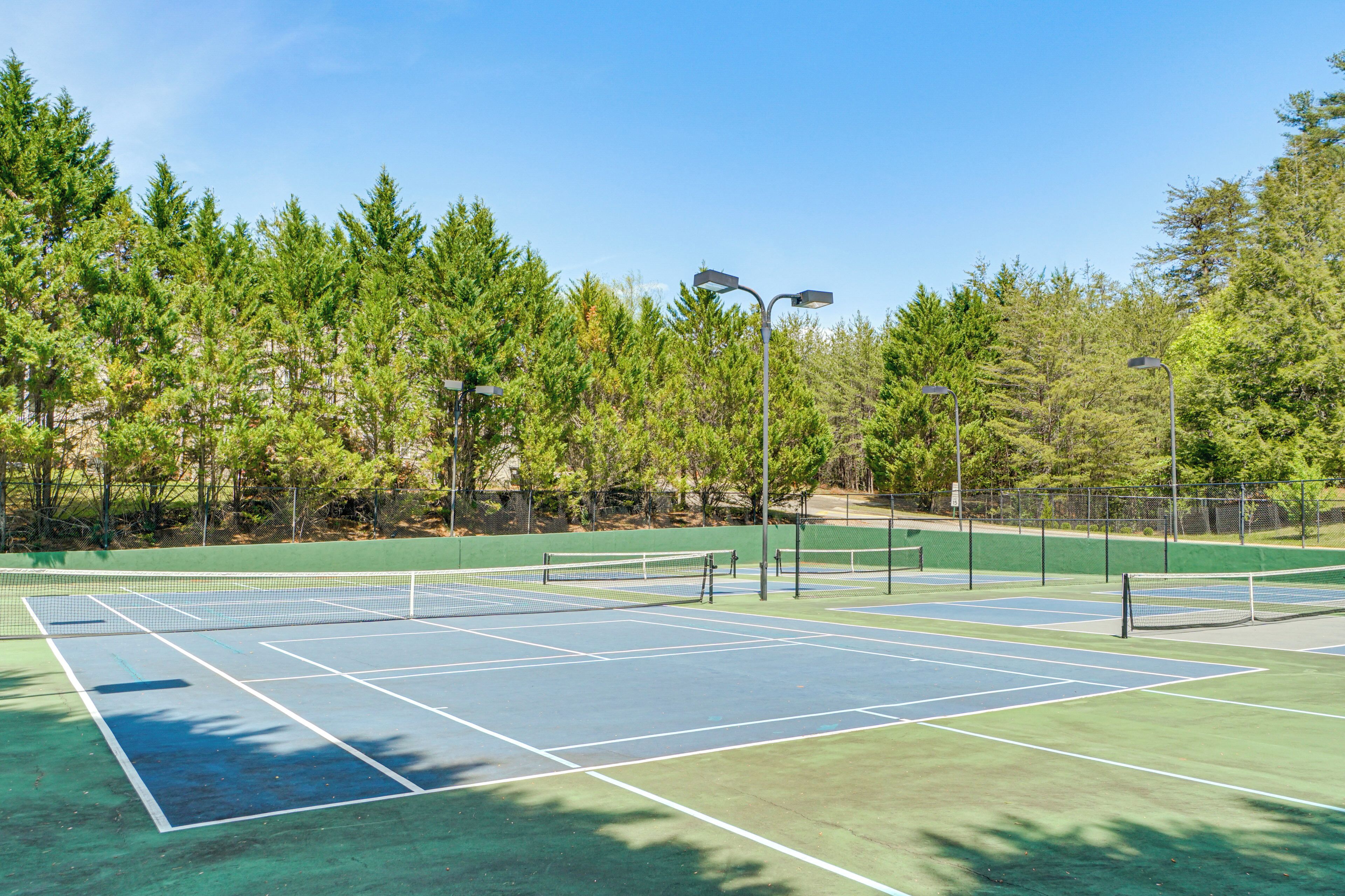 Una cancha de tenis con red, rodeada de árboles.