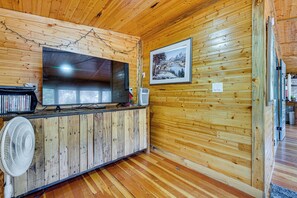 Un interior de fusta amb televisió de pantalla plana, un ventilador i un quadre al mur.