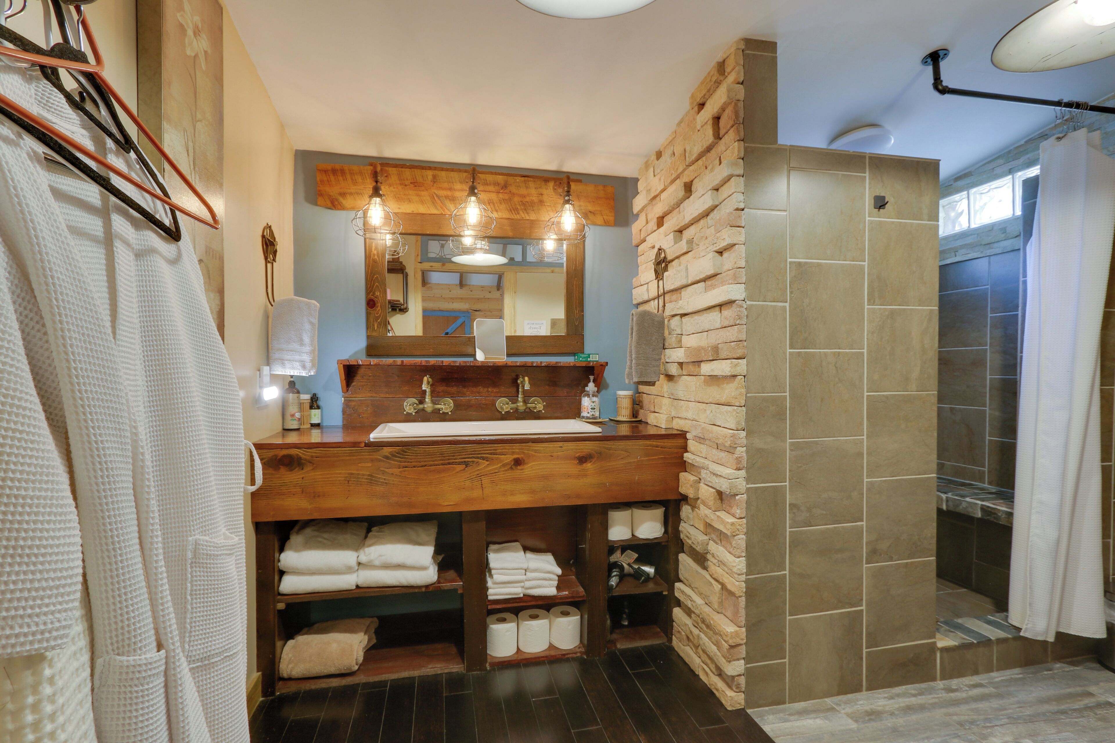 A bathroom with a wooden vanity, a large mirror, and a shower area.