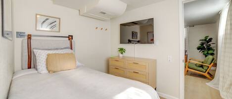 A bedroom with a bed, dresser, mirror, and a chair.