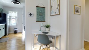 A modern kitchen with wooden flooring, a white dining table with a grey chair, a ceiling light, and a wall-mounted plant. - Walkable Apt in Dtwn Caldwell! Near Campus Events (Caldwell)