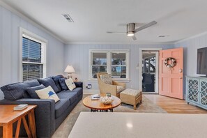 Una sala de estar con sofá, sillón, mesa de centro y una puerta que da a un espacio exterior.