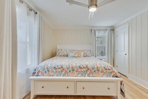 Un dormitorio con cama, ventilador de techo, ventana y puerta.