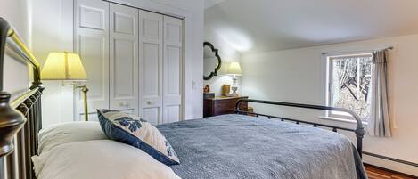 Un dormitorio con cama, ventilador de techo, ventana con cortinas y una puerta.