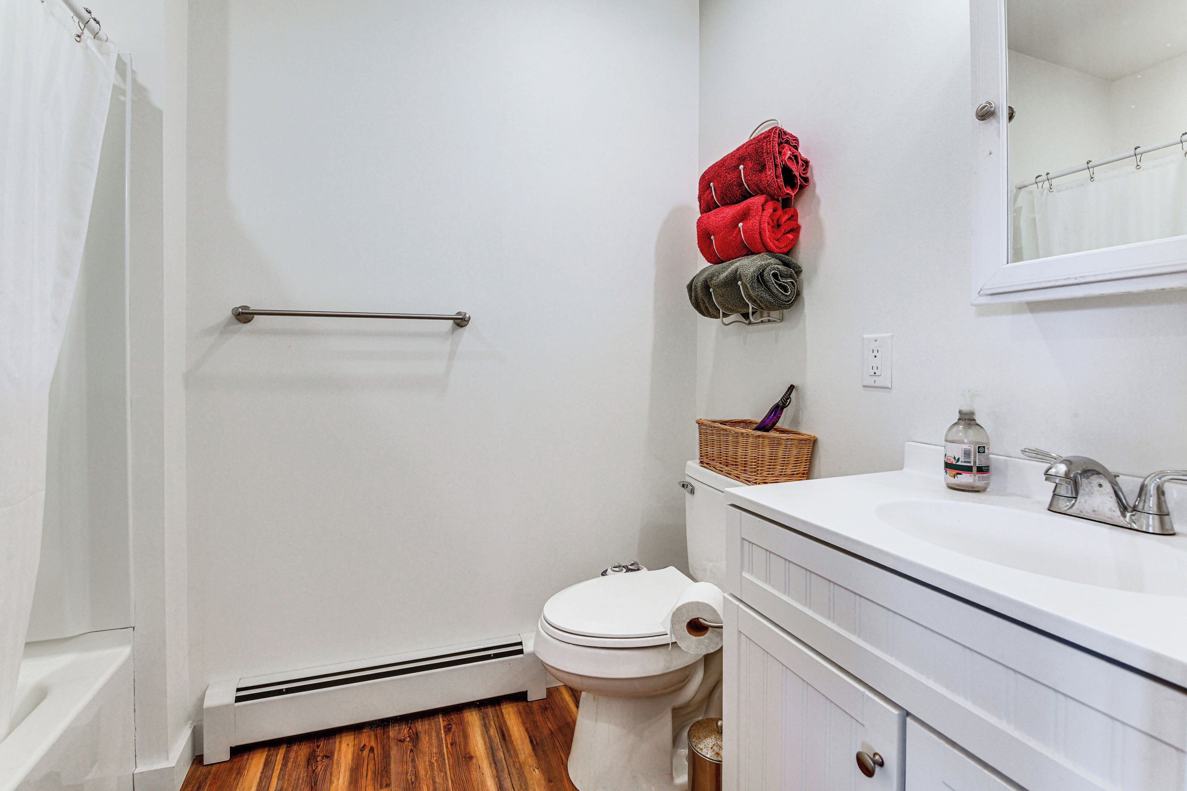 Un bagno con un WC bianco, un lavandino bianco, uno specchio e una tenda da doccia.