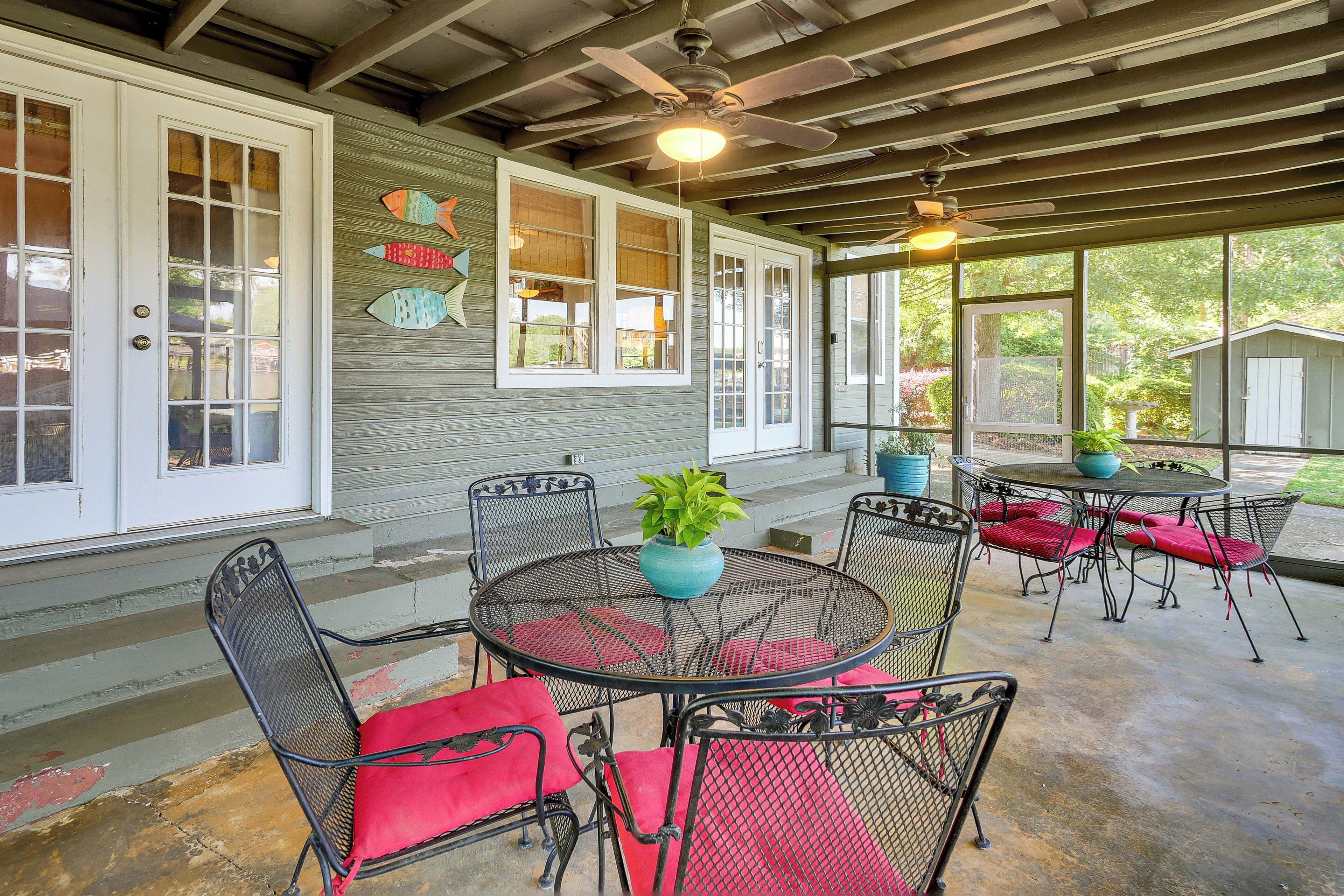 A covered patio with metal chairs and a table, a ceiling fan, and a potted plant.