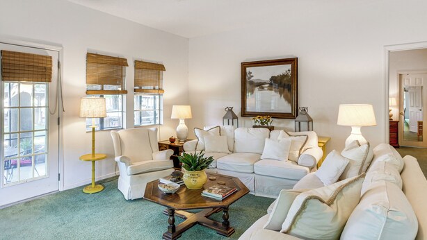 A living room with a sofa, armchairs, a coffee table, and a painting on the wall.