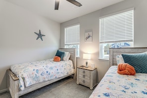 Une chambre avec deux lits, une table de chevet, une décoration en forme d’étoile de mer et une fenêtre avec des stores.
