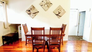 A dining area with a wooden table and chairs, a bench, and three wall-mounted floral paintings. - Near Oregon Caves: 2-studio Retreat w/ Game Room! (Cave Junction)