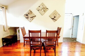 Un comedor con una mesa y sillas de madera, un banco y tres cuadros florales colgados en la pared.