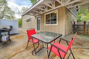 A small building with a covered patio, a table with chairs, and a propane tank outside. - Near Oregon Caves: 2-studio Retreat w/ Game Room! (Cave Junction)