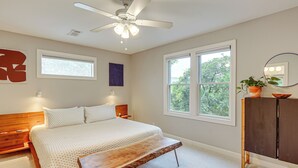 A bedroom with a bed, bedside tables, a wooden bench, a ceiling fan, windows, a dresser, and a potted plant. - Old Austin Vibes! Spacious Yard & Porch Near UT (Austin)