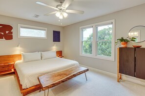 A bedroom with a bed, bedside tables, a wooden bench, a ceiling fan, windows, a dresser, and a potted plant. - Old Austin Vibes! Spacious Yard & Porch Near UT (Austin)