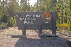 Un panneau indiquant l’entrée du parc national de Yellowstone, avec un logo et du texte.