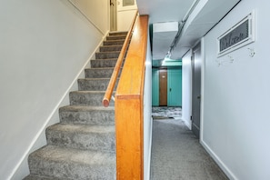 A carpeted staircase with a wooden handrail, a 'Welcome' sign, and a teal door in the background. - Walk to Parks & Dining: Central Idaho Falls Home (Idaho Falls)