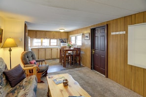 A compact living space with a sofa, a dining table, a chair, a lamp, and a kitchen area with wooden cabinets and a refrigerator. - 6 Blocks to Yellowstone NP: 'bison Home' w/ BBQ (West Yellowstone)