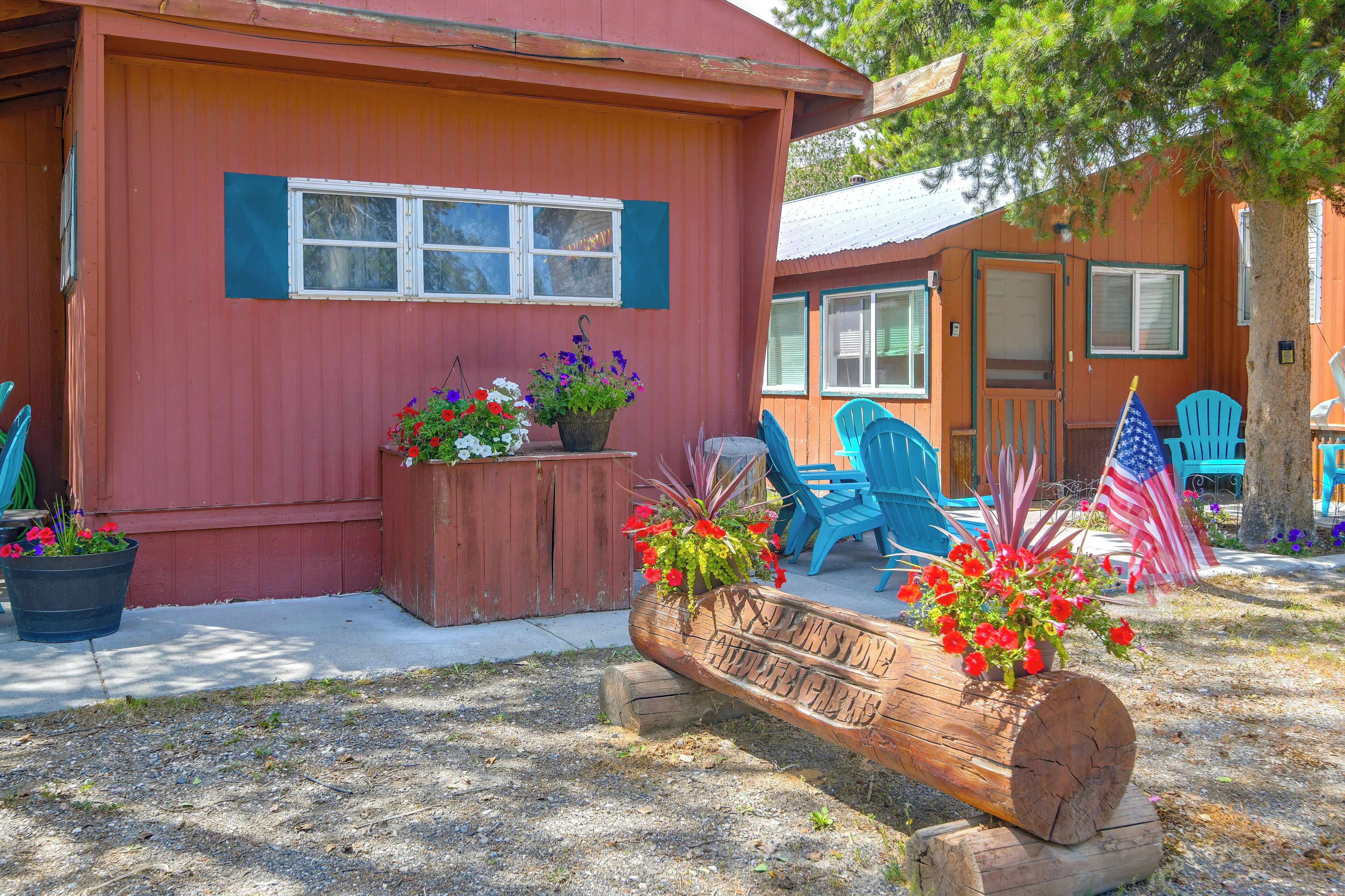 A red building with a porch, potted plants, and outdoor seating.