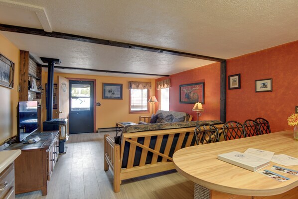 A cozy room with a wooden bench, a dining table, and a television. - Gateway to Yellowstone! Cabin < 1 Mi to Nat'l Park (West Yellowstone)