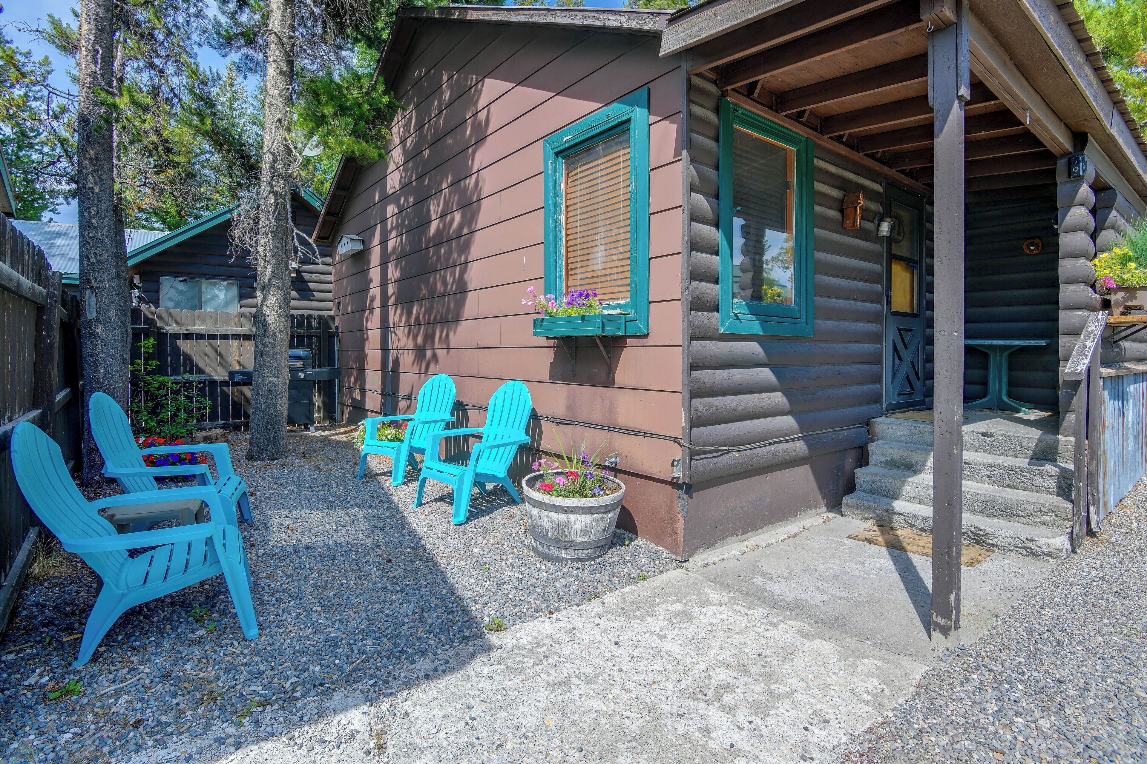 A log cabin with a porch, outdoor seating, and a gravel driveway.