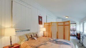 Une chambre avec un grand lit, deux lampes de chevet, une cloison en bois et un panneau décoratif encadré au mur.
