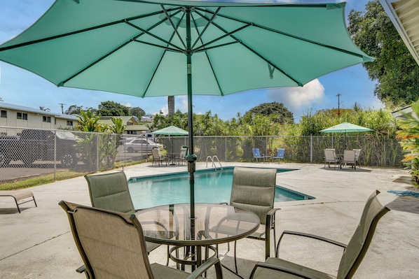A backyard with a swimming pool, outdoor furniture, and a green umbrella. - Walk to Dining & Local Markets! Hilo Getaway (Hilo)