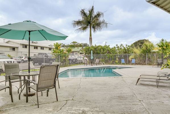 Un espace piscine aménagé avec des chaises longues, une table et un parasol.